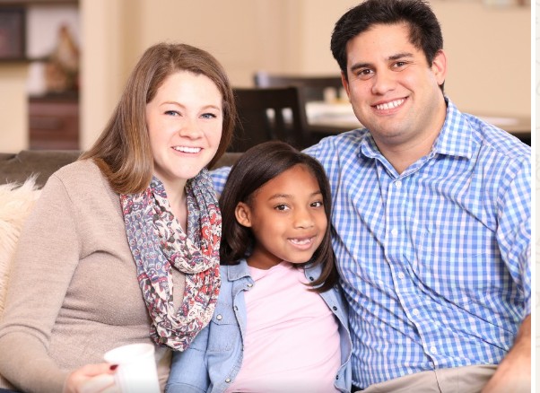 Smiling foster family sitting together at home